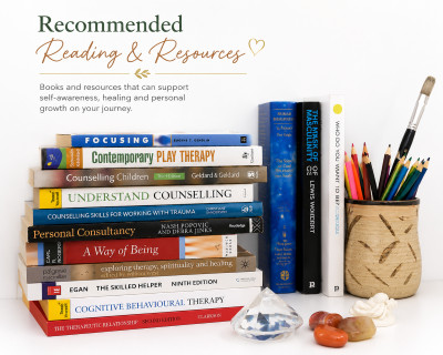 Recommended reading, a stack of counselling and therapy books beside a pot of coloured pencils