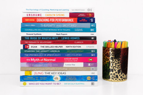 A stack of books on therapy, coaching and personal growth